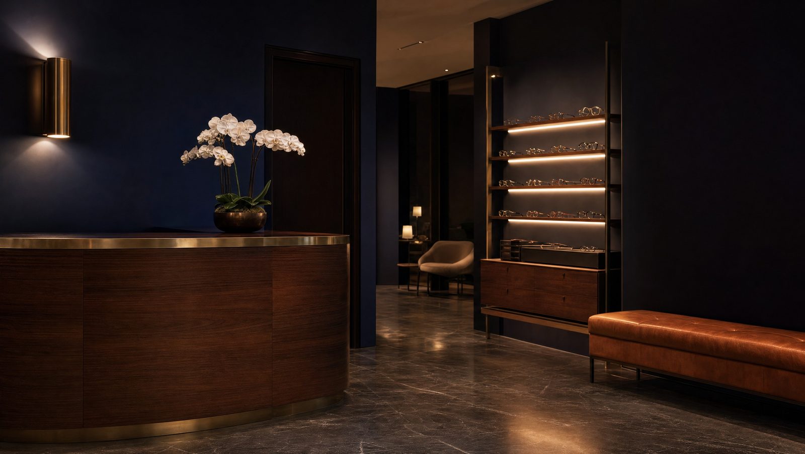 A quiet reception area with a walnut desk, brass sconce, and leather bench
