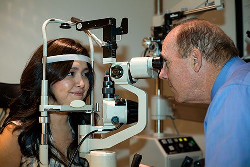 An optometrist examining a patient's eyes at the slit lamp